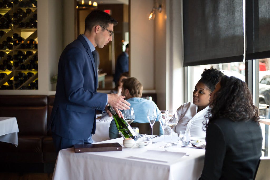 a waiter showing a bottle of wine to the customers